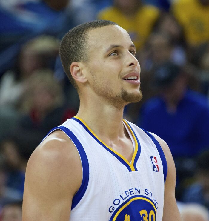 Basketball player in Golden State Warriors jersey during game, representing highest paid athletes 2025.
