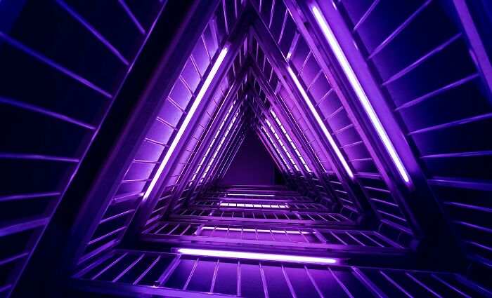 Interior view of a Danish prison cell with modern purple lighting and triangular geometric design.