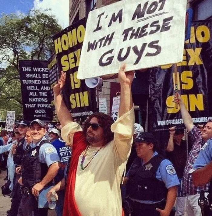 Man dressed as Jesus holding a sign saying not with these guys at a chaotic good protest for justice and rights.