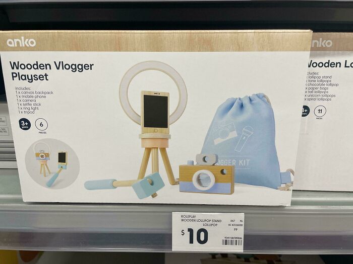 Wooden vlogger playset with tripod, phone, selfie stick, ring light, and camera, displayed on store shelf priced at 10 dollars.