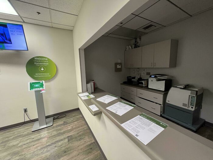 Reception area with check-in kiosk and medical equipment in a dimly lit room depicting a dystopian scene in the US.