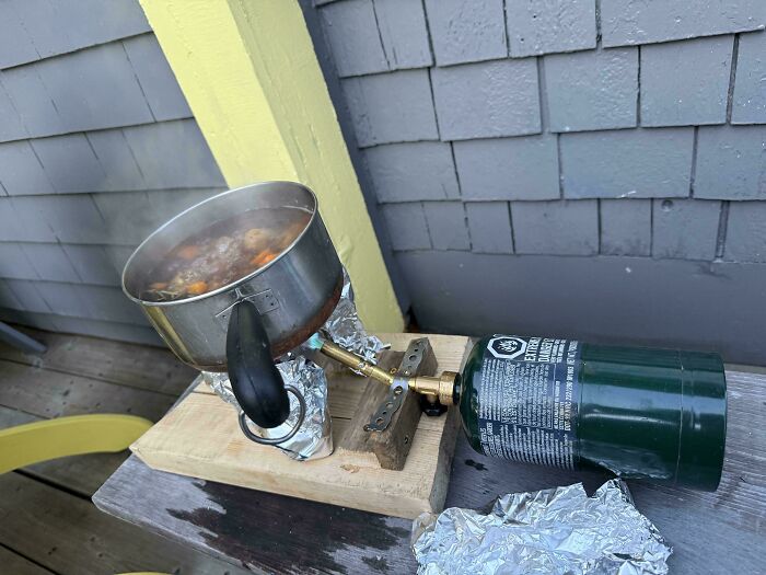 Homemade outdoor stove made from propane tank and aluminum foil, showcasing redneck engineer ingenuity and practical design.