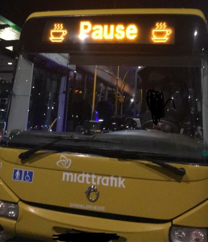 Yellow midttrafik bus at night with digital sign displaying Pause and coffee cup icons, illustrating Danish urban transport scene.