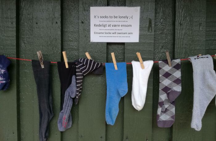 Socks hanging on a line with a sign about loneliness in a Danish prison cell setting.