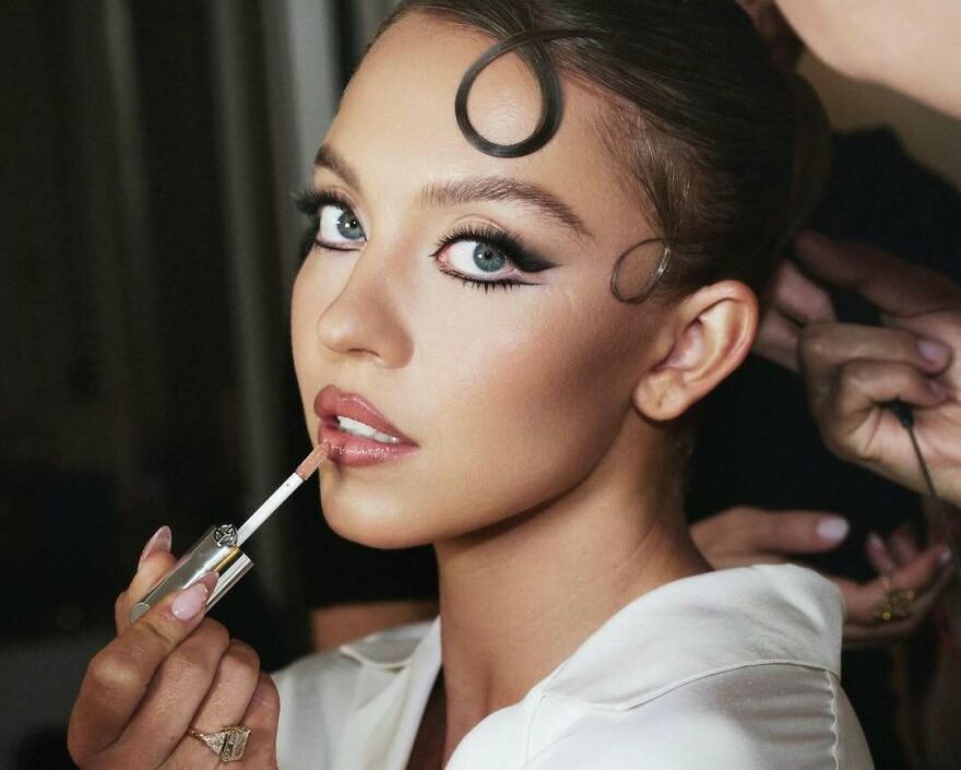 Sydney Sweeney getting makeup applied, showcasing the polished look behind her business ventures and net worth in 2025. Sydney Sweeney getting makeup applied, showcasing the polished look behind her business ventures and net worth in 2025.