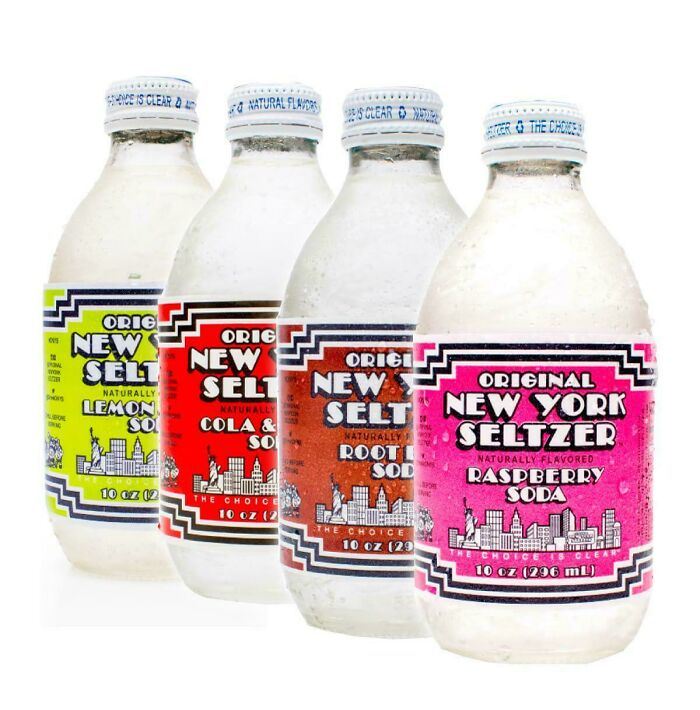 Four vintage New York Seltzer soda bottles in lemon-lime, cola, root beer, and raspberry flavors, evoking old nostalgia.
