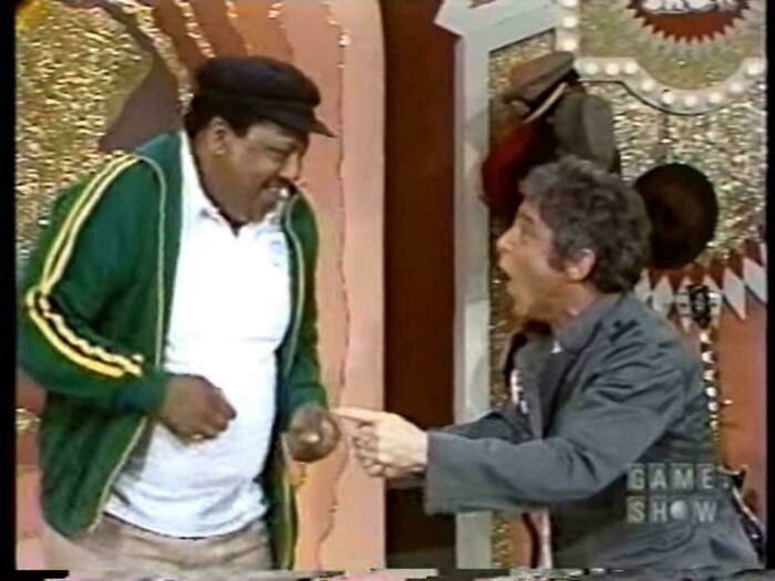 Two men in vintage TV setting, one laughing and pointing, evoking nostalgia and childhood memories to feel old as heck.