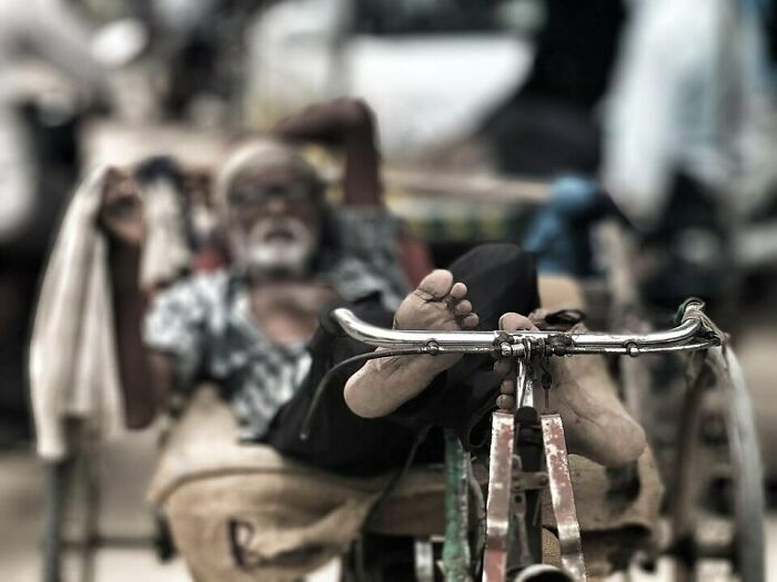 An elderly man relaxing on a rickshaw captured in street photography showcasing humanity in its purest form.