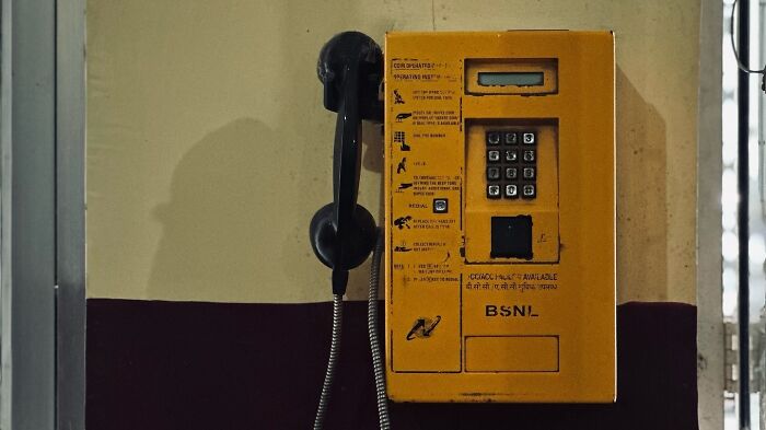 Yellow public payphone mounted on a wall, showcasing street photography that captures humanity through Snehal Dudekula’s lens.