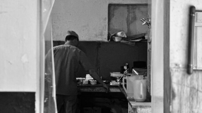 Man working in a dimly lit room, captured with street photography that reflects humanity in its purest form.