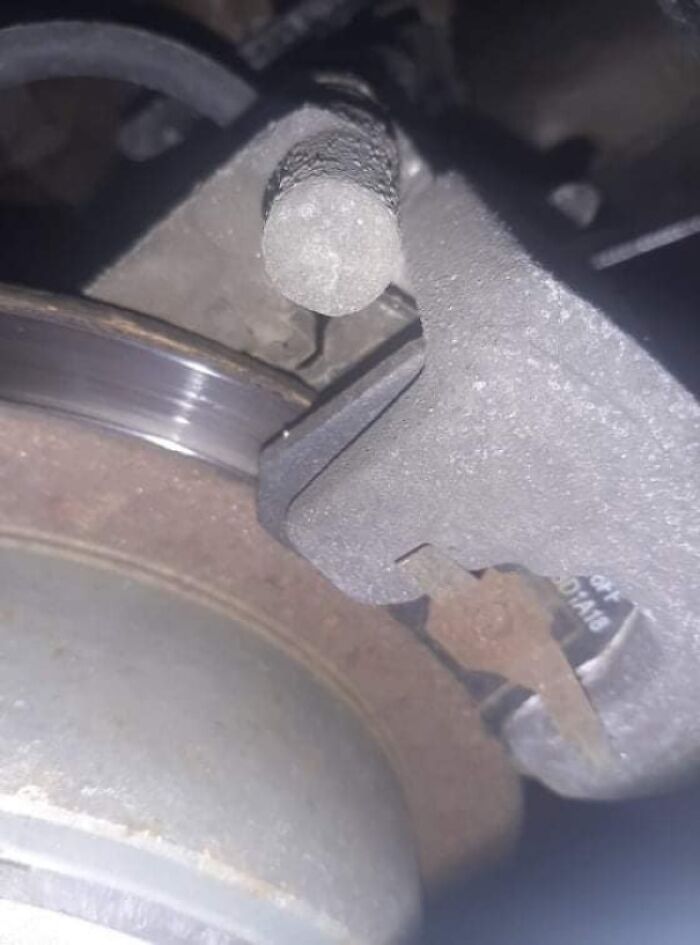 Close-up of a car brake caliper and rotor showing wear and rust, illustrating challenges car mechanics face.