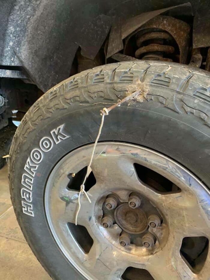 Car mechanic showing a tire with a rusted nail and wire stuck in the tread as proof of damage being dealt with.