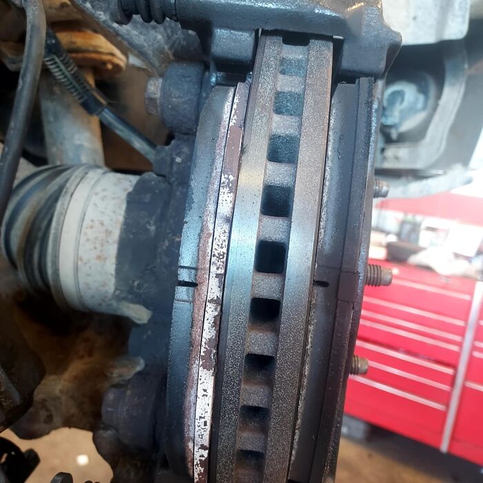 Close-up of car brake rotor and caliper showing wear and rust, illustrating a mechanic's repair challenge.