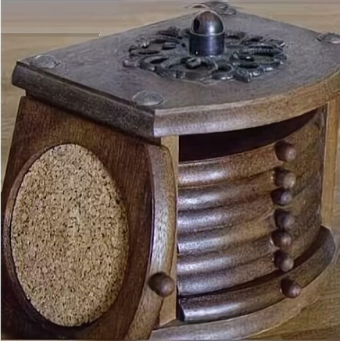 Wooden vintage coaster holder with carved decorative top and cork coasters inside, evoking nostalgic memories of old age.