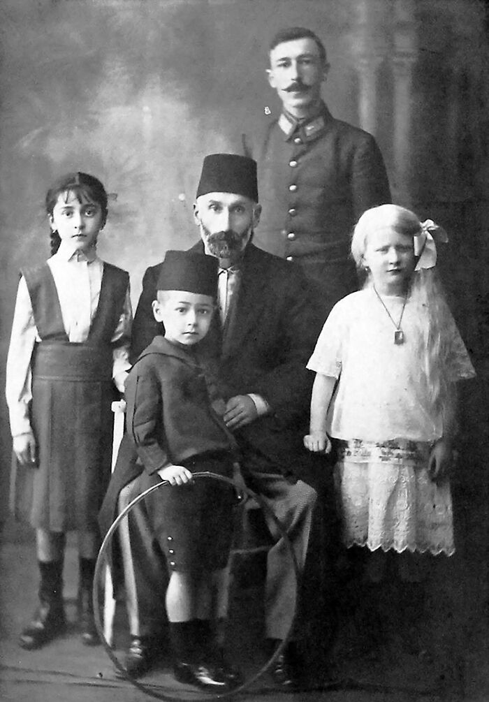 Vintage black and white family portrait showing people’s lives from a different time with traditional clothing and toys.