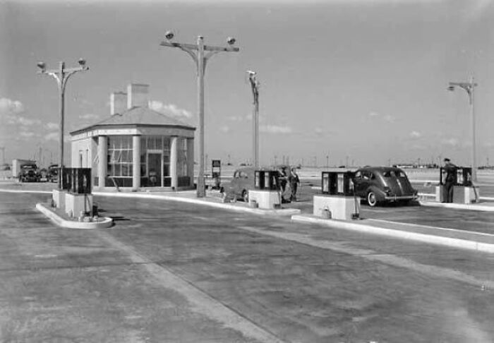 Vintage gas station with classic cars and attendants showing people’s lives from a different time in black and white.