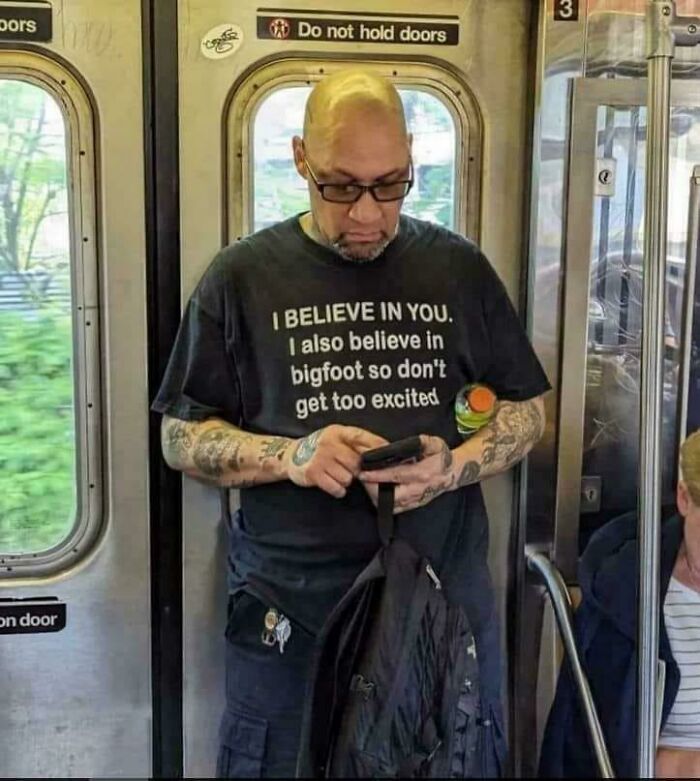 Man wearing a funny shirt about Bigfoot on a subway, illustrating bizarre images combining the holy and the cursed.