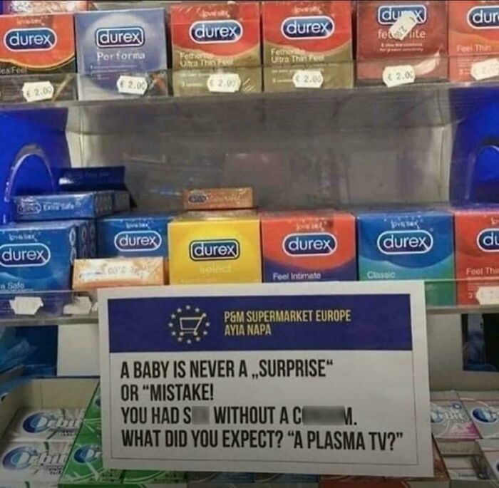 Condoms displayed above a humorous sign about babies, combining funny and bizarre elements with holy and cursed themes.