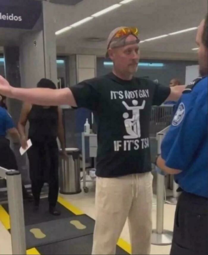 Man wearing a humorous shirt at airport security, illustrating a funny and bizarre image combining the holy and the cursed.
