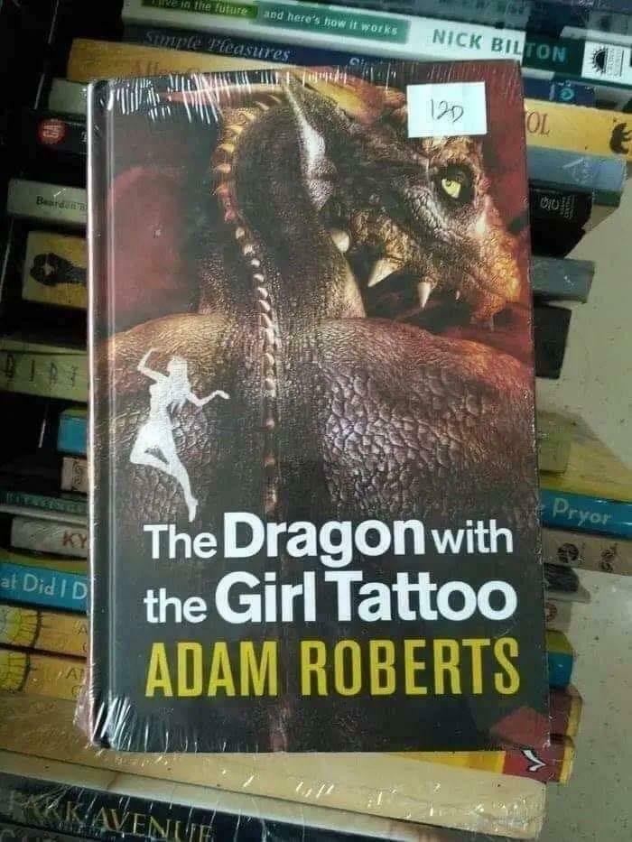 Book titled The Dragon with the Girl Tattoo by Adam Roberts with dragon illustration among stacked books, funny and bizarre image.