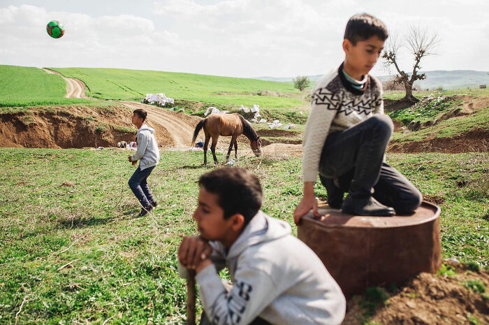 Three boys playing outdoors in a rural landscape in Turkey, showing the candid side of life captured by Yusuf Aksoy.
