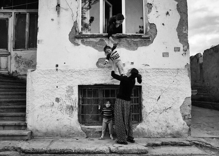 Black and white candid photo by Yusuf Aksoy showing the real side of life with family in Turkey’s worn urban setting.