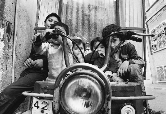 Children sitting candidly on a rustic vehicle, capturing the real, candid side of life in Turkey by Yusuf Aksoy.
