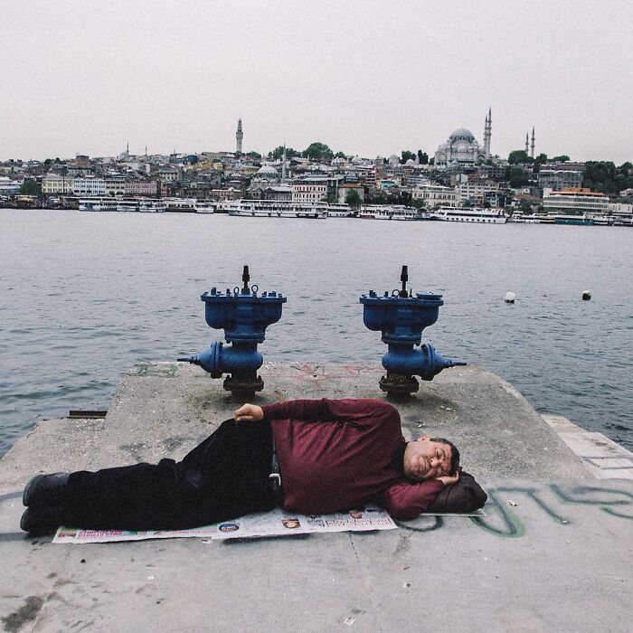 Man resting by the water on a pier in Turkey, captured candidly showing the real side of life by Yusuf Aksoy.