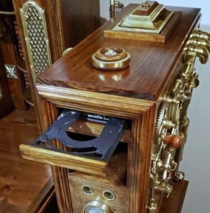 Antique wooden steampunk-style device with brass gears and a modern CD drive tray, a funny and bizarre combination of holy and cursed.