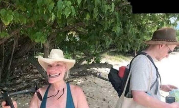 Two people on a beach, one with a distorted funny smile wearing a sunhat, combining holy and cursed image humor.