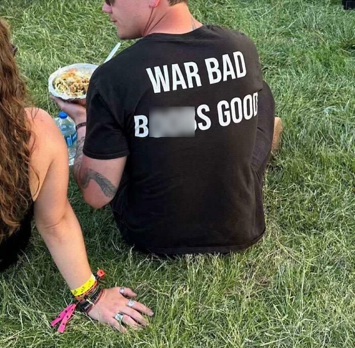 Man wearing a black shirt with ironic text sitting on grass, part of funny and bizarre images combining the holy and the cursed