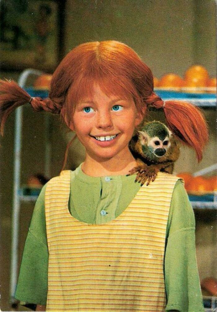 Young girl with red pigtails smiling with a small monkey on her shoulder, evoking nostalgia and feel old moments.