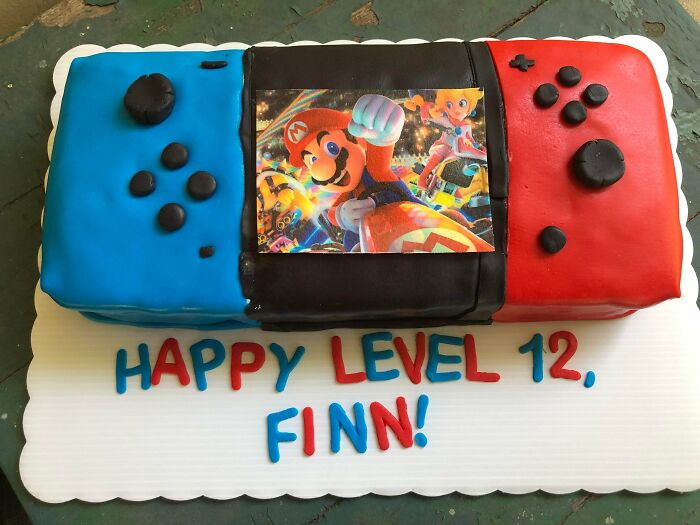 Colorful baked goods cake shaped like a Nintendo Switch with Mario image celebrating a 12th birthday.