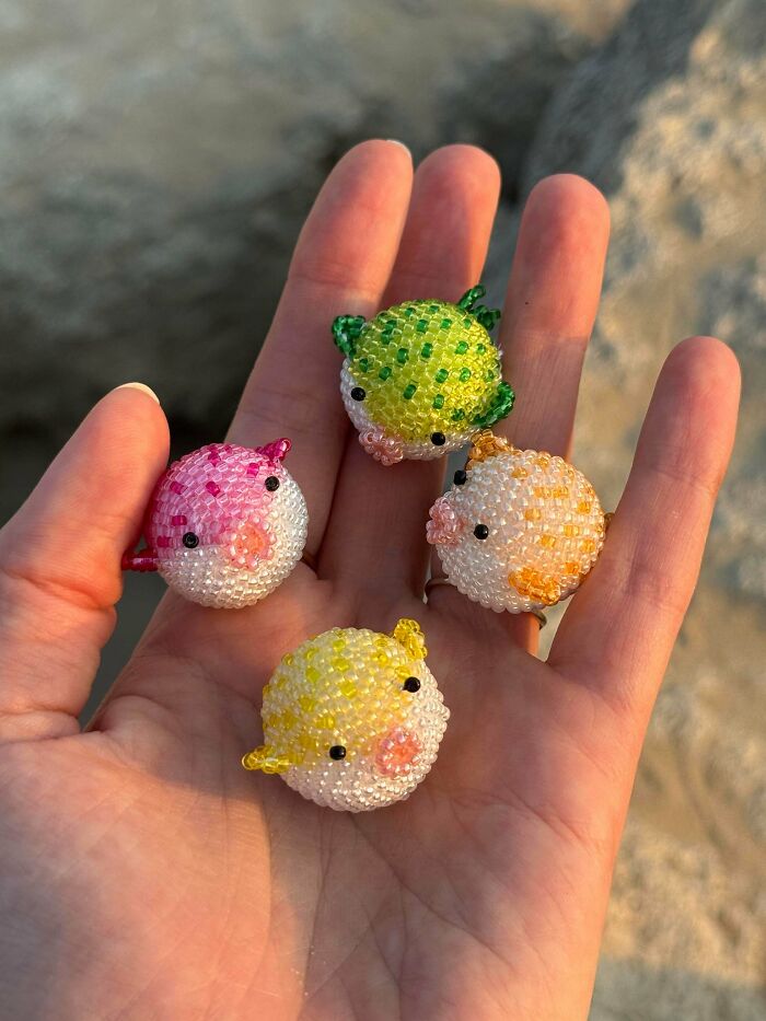 Tiny handmade beaded animals in pink, yellow, orange, and green, held delicately in a person's hand, showcasing cool crafts.