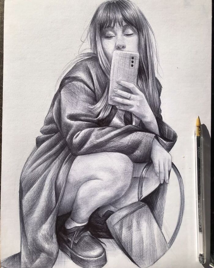 Hyperrealistic ballpoint pen portrait of a woman crouching and holding a phone next to the actual pen used for drawing.