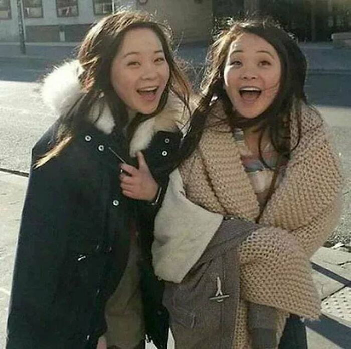 Two women smiling warmly outdoors, radiating joy and positivity in a heartwarming moment to cleanse negativity.