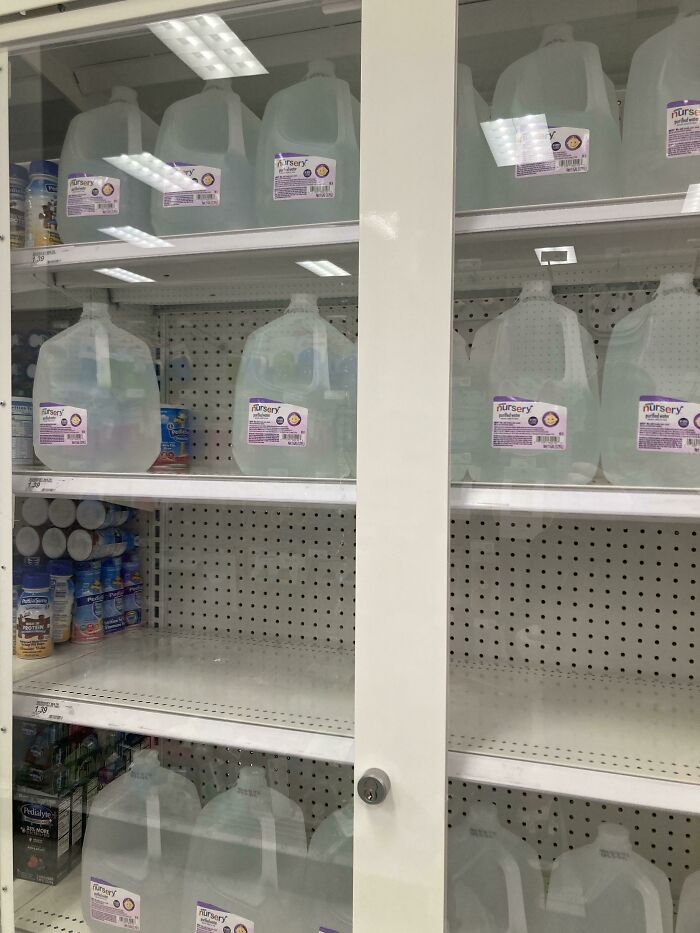 Shelves with limited water supply in a US store, highlighting real-life dystopian scenes and shortages.