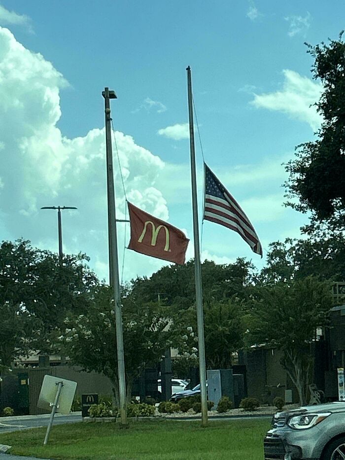 American and McDonald's flags flying at half-mast outside a restaurant, representing dystopian real-life scenes in the US.
