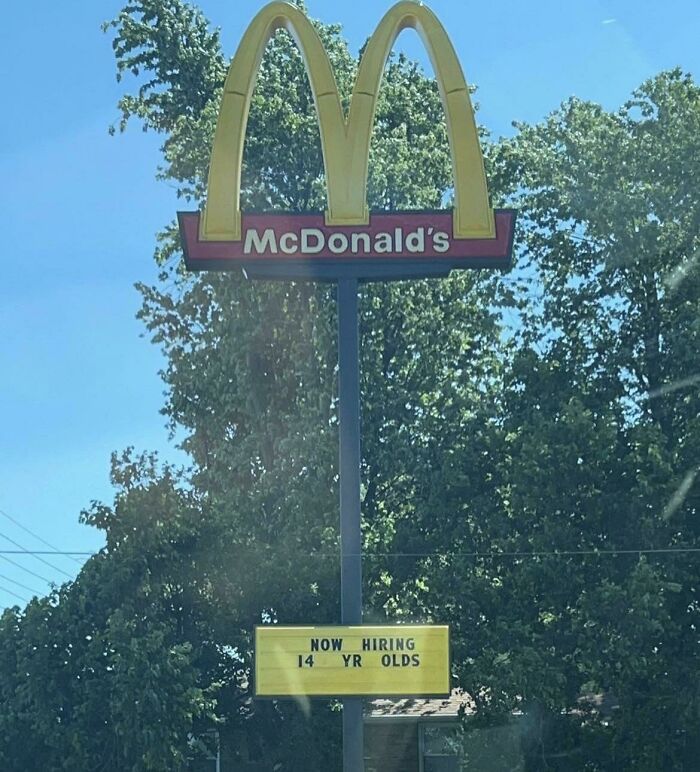 McDonald's hiring sign for 14-year-olds outside a restaurant in a real-life dystopian scene in the US.