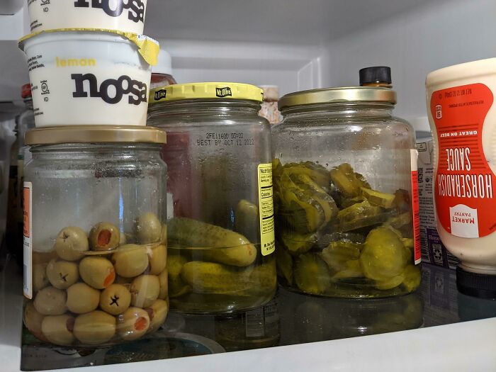 Jars of pickles and olives mixed together in a fridge, illustrating awful roommates and frustrating food situations.