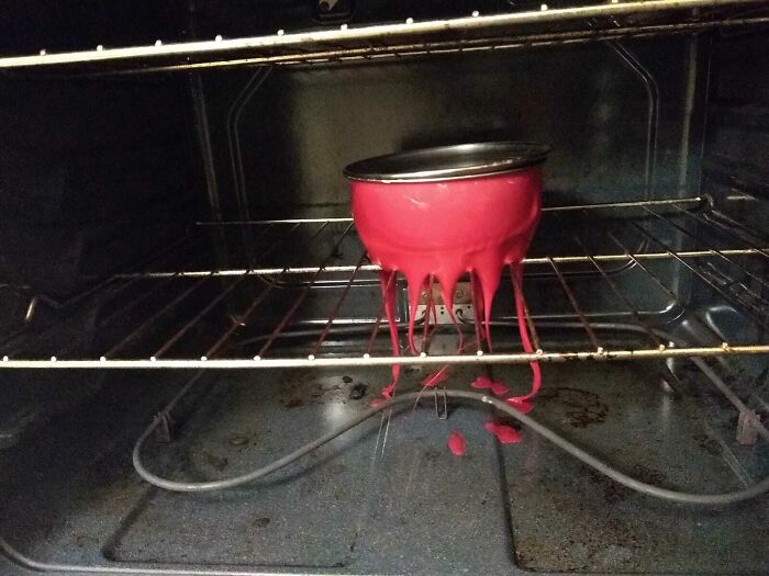 Baking mishap with red batter overflowing from a bowl inside a dirty oven showing awful roommate problems.