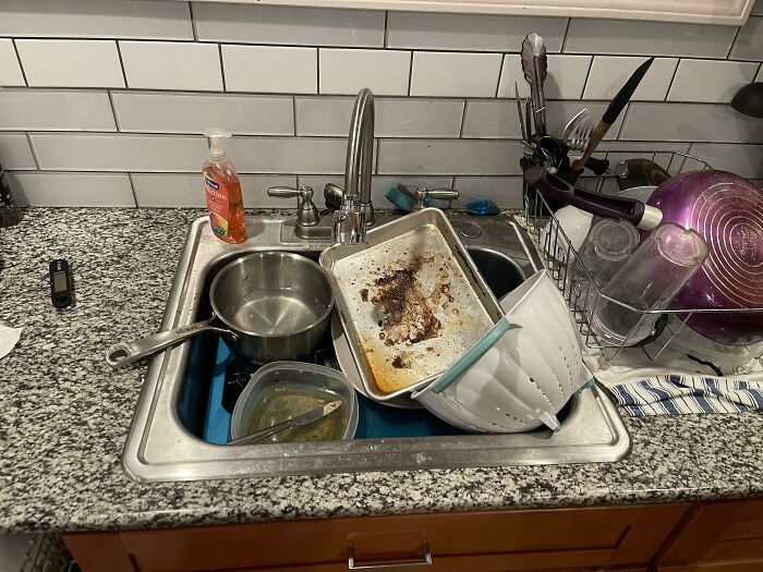 Dirty dishes piled high in a kitchen sink illustrating awful roommates and messy living spaces frustration