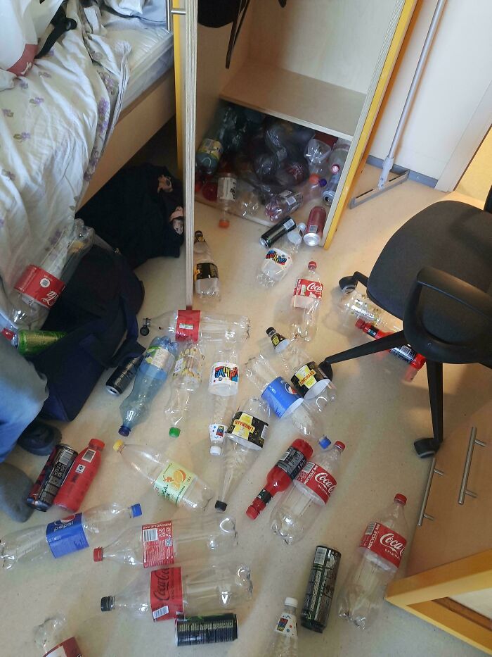 Messy room with dozens of empty plastic bottles scattered on the floor, highlighting awful roommates behavior.