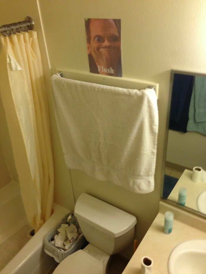 Bathroom with overflowing trash can and towel blocking mirror, highlighting awful roommate behavior in shared living space.