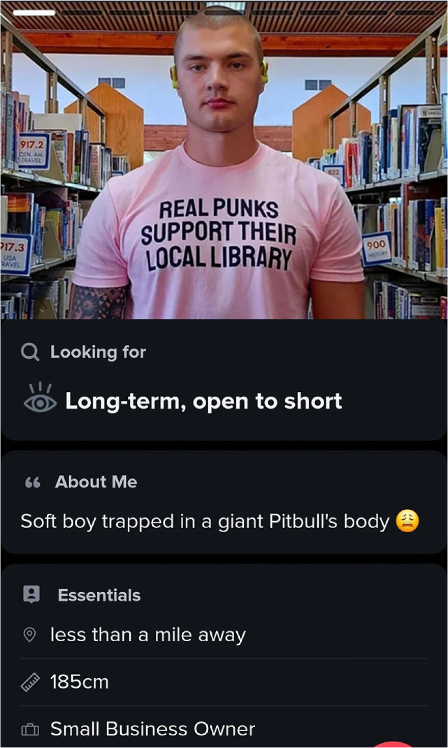 Man with a tattoo wearing a pink shirt in a library, featured in Tinder bios for guys inspiration for dating profiles.