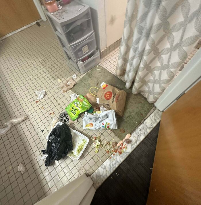 Trash and food wrappers strewn on a bathroom floor, illustrating awful roommates and enraging messy living spaces.