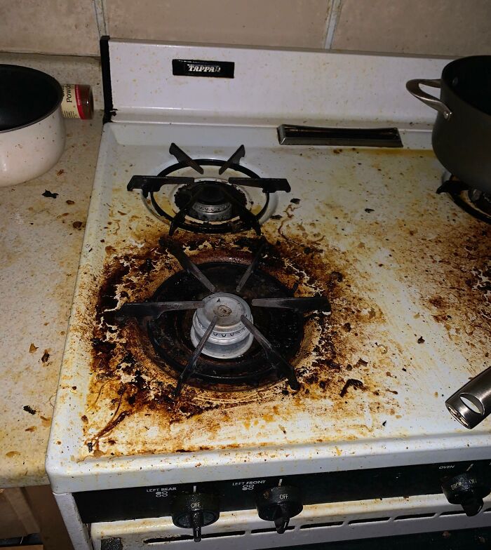 Dirty stove covered in grease and burnt food stains, illustrating awful roommate cleaning habits and mess.
