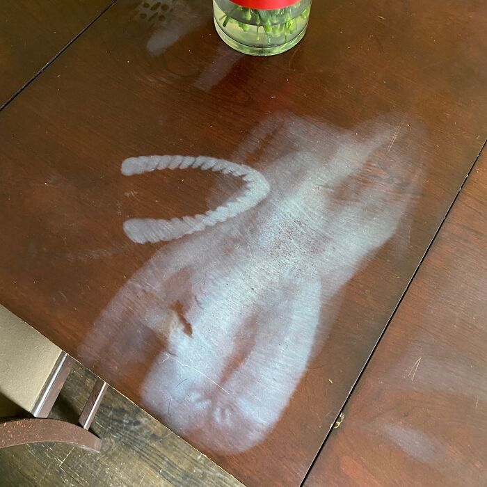 Dusty wooden table with a dirty handprint and smiley face showing signs of awful roommates neglecting cleaning.