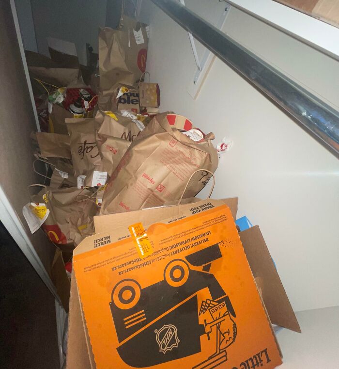 Trash and fast food bags cluttered along a narrow hallway, showing a prime example of awful roommate behavior.