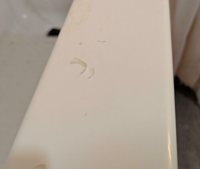 Chipped white bathtub edge showing damage caused by awful roommates in a shared living space.